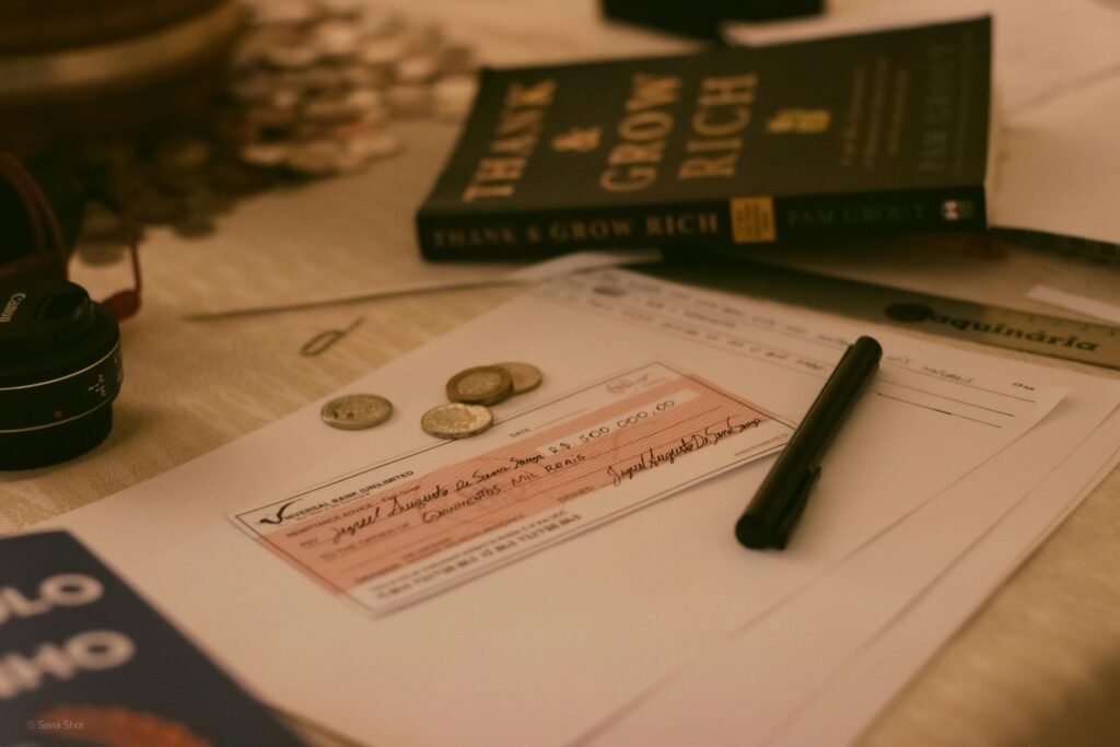 Close-up of a business desk with a check, coins, pen, and financial books, creating a financial planning vibe.